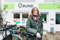 Eine Frau steht vor einem Haus, darüber ist ein Schild mit der Aufschrift BUND Bremen.