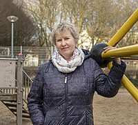 Erzieherin Tetiana Mykhailiuk steht auf einem Spielplatz an einem Klettergerüst und hält sich mit einer Hand daran fest