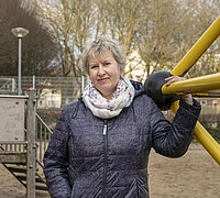 Erzieherin Tetiana Mykhailiuk steht auf einem Spielplatz an einem Klettergerüst und hält sich mit einer Hand daran fest