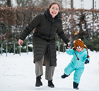 Eine junge Frau hält ein kleines Mädchen an der Hand.