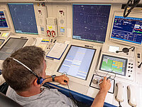 Sven Wilke sitzt an seinem Arbeitsplatz in der Radarkontrollzentrale Bremen und steuert den Flugverkehr an mehreren Radar- und Informationsbildschirmen.