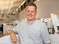 Porträt von Sven Wilke, Fluglotse in der Radarkontrollzentrale Bremen, lächelnd vor seinem Arbeitsbereich.