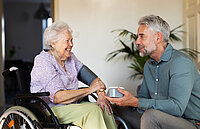 Ein Sohn mit seiner pflegebedürftigen Mutter im Rollstuhl.