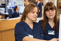 Zwei Pflegerinnen, die etwas besprechen.