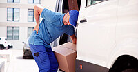 Ein Mitarbeiter im Paketlieferdienst hält sich den Rücken