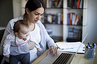 Mutter mit Kind sitzt am Laptop 