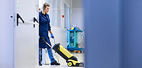 Eine Frau saugt einen Flur in einer Firma