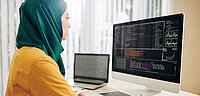 Frau mit Kopftuch am Arbeitsplatz vor dem Computer