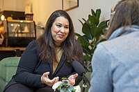 Eine Frau sitzt in einem Stuhl und unterhält mit einer anderen Person