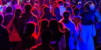 Mehre junge Menschen stehen auf einem Konzert im roten Licht