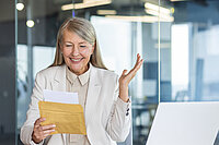 Eine Frau öffnet den Umschlag mit ihrem Arbeitszeugnis