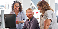 Drei Personen unterhalten sich im Büro