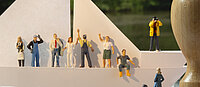 Diverse Miniaturfiguren, die auf einem Boot sind und sich auf dem Weg zu einem Stempel befinden.