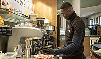 Ladji Diarra bedient die Kaffeemaschine in einer Bäckerei