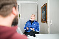 Eine Frau sitzt auf einem Stuhl und gestikuliert mit den Händen.