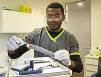 Ein Zahnmedizinische Fachangestellter hantiert mit Werkzeug in einer Zahnarztpraxis.