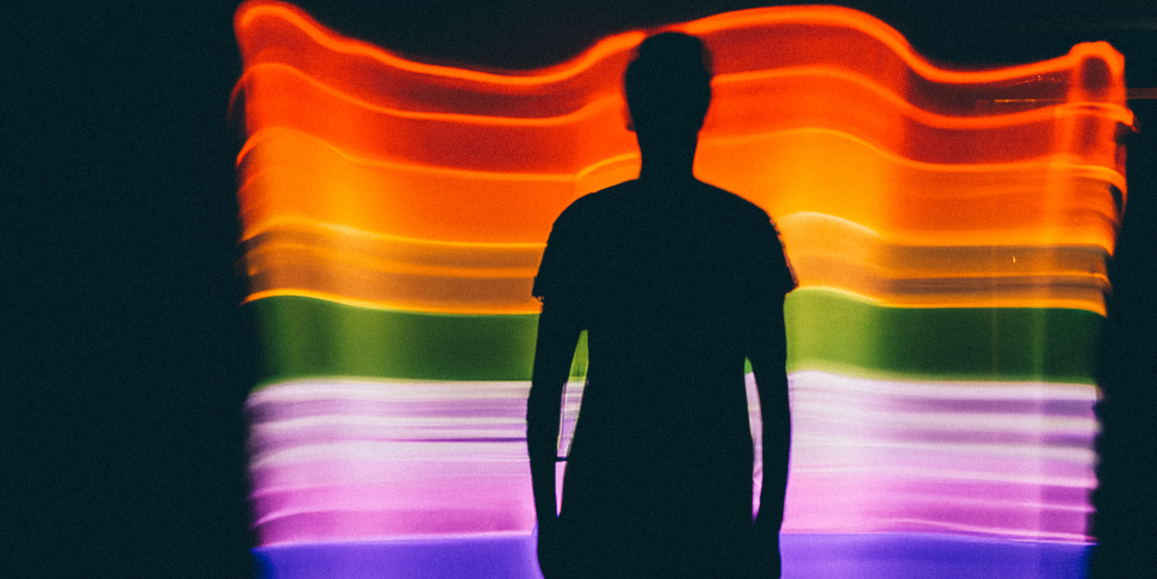 Schatten eines Menschen vor einer Art Regenbogenflagge